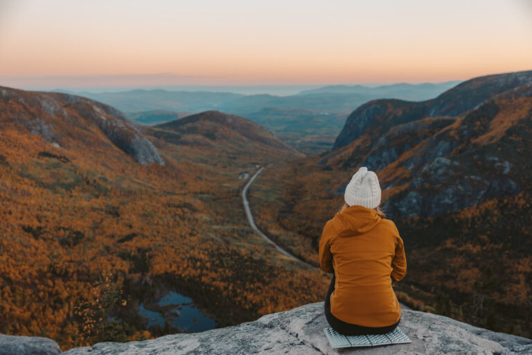 person sitting at summit of mont du dome in quebec during peak fall foliage season
